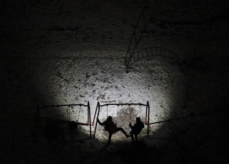 Ungmenni á leikvelli í svarta myrkri vegna rafmagnsleysis í Kíev. Mynd: EPA