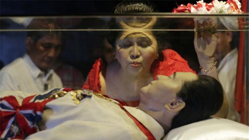 Ástin lifir. Lík Marcosar var lengi vel geymt í húsi fjölskyldunnar og jafnvel haft til sýnis. Hér smellir Imelda kossi á glerhjúpinn sem varði smurðan líkama einræðisherrans.