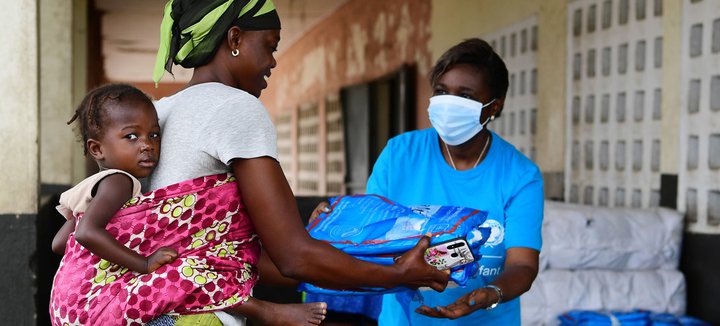 Móðir tekur við nauðsynjum frá starfsmanni UNICEF á Fílabeinsströndinni.