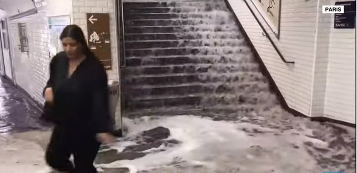 Rigningarvatn flæðir niður stiga á neðanjarðarlestarstöð í París í gær.
