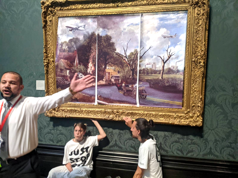 Þau Hannah Hunt og Eben Lazarus sitja á gólfi eins sýningarsalar National Gallery í London, búin að líma sig föst við Heyvagninn eftir John Constable. Mynd: Just Stop Oil