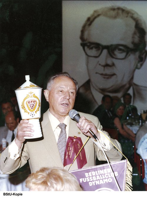 Mielke hampar verðlaunagrip. Í bakgrunni má sjá mynd af Erich Honecker (Kinokalender).