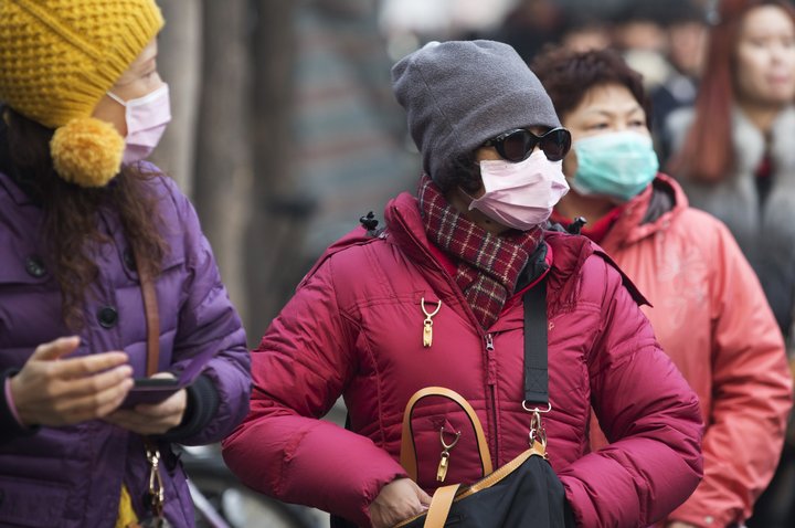 Fólk setur grímur fyrir vit sín til að vernda sig gegn menguninni.