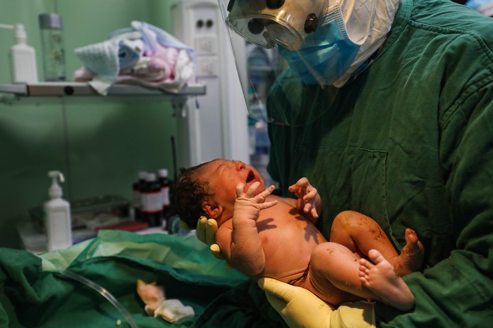 Ljósmóðir tekur á móti barni á sjúkrahúsi í Wuhan-borg í Kína. Vegna gruns um að móðirin væri smituð af kórónuveirunni var gripið til mikilla varúðarráðstafana við fæðinguna.