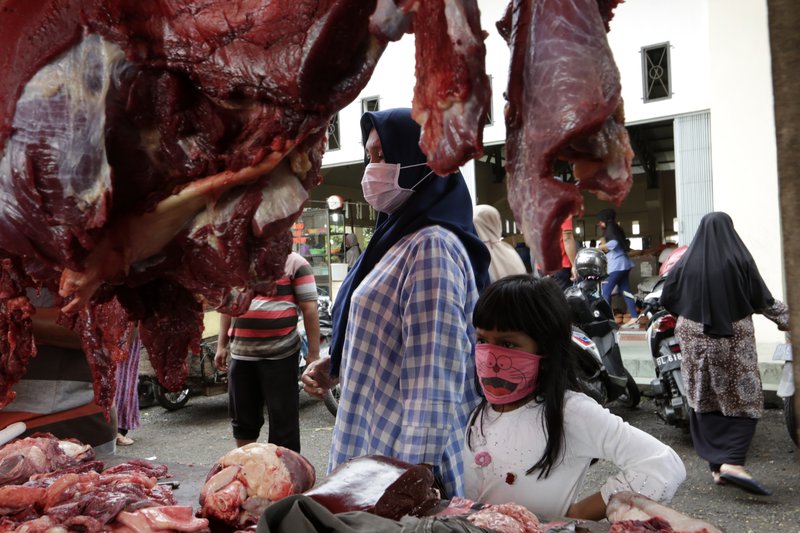 Stúlka í Indónesíu horfir á kjötstykki á útimarkaði. Mynd: EPA