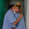 Hjúkrunarfræðingar á sjúkrahúsi í Belgíu hugga hvor annan eftir að einn sjúklingurinn á COVID-deild lést.