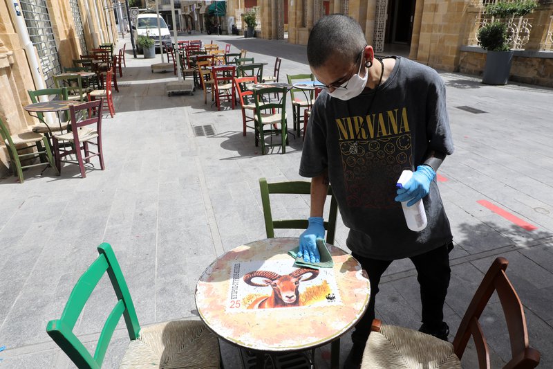 Þjónn á veitingastað á Kýpur sótthreinsar borð fyrir gesti. Mynd: EPA