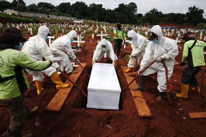 Ítrustu varúðar gætt við greftrun manneskju sem lést vegna COVID-19 í Indónesíu. Hálf milljón Indónesa hafa greinst með veiruna.