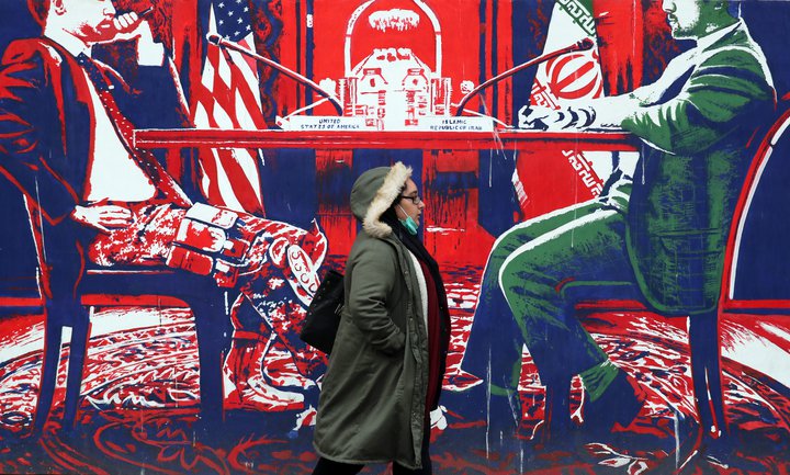 Kona á gangi fyrir framan veggmynd í Teheran þar sem valdatafli Bandaríkjanna er mótmælt.