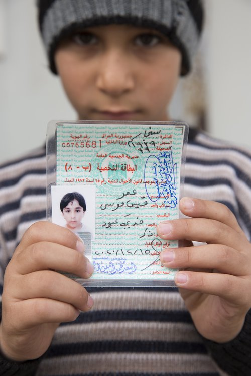 Ungur drengur sem hefur verið á vergangi með fjölskyldu sinni frá orrustunni í Mósúl sýnir nýútgefið fæðingarvottorð sitt. Vottorðið veitir honum loks aðgang að menntun og heilbrigðisþjónustu í Írak. Mynd: EPA