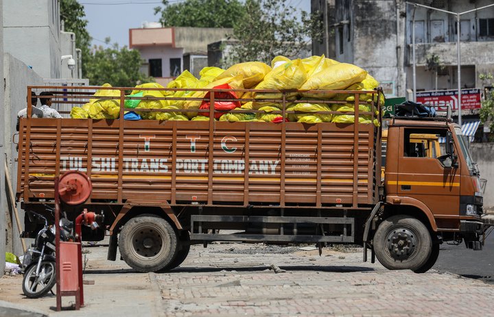 Heilbrigðisstarfsmaður á COVID-spítala í Ahmedabad á Indlandi fyllir bíl af úrgangi sem fellur til við meðhöndlun sjúklinga.