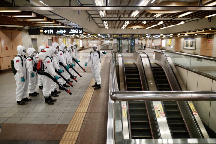 Flokkur hermanna með sótthreinsibúnað að vopni bíður sig hér undir að leggja til atlögu gegn veirunni á lestarstöð í Taipei undir lok síðasta mánaðar.