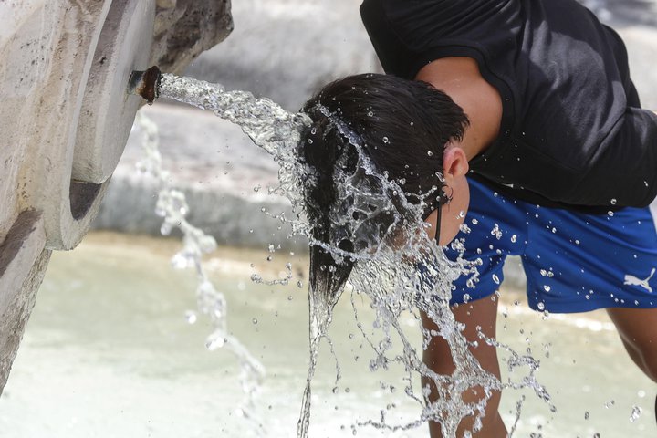 Maður kælir sig niður í ítölskum gosbrunni.