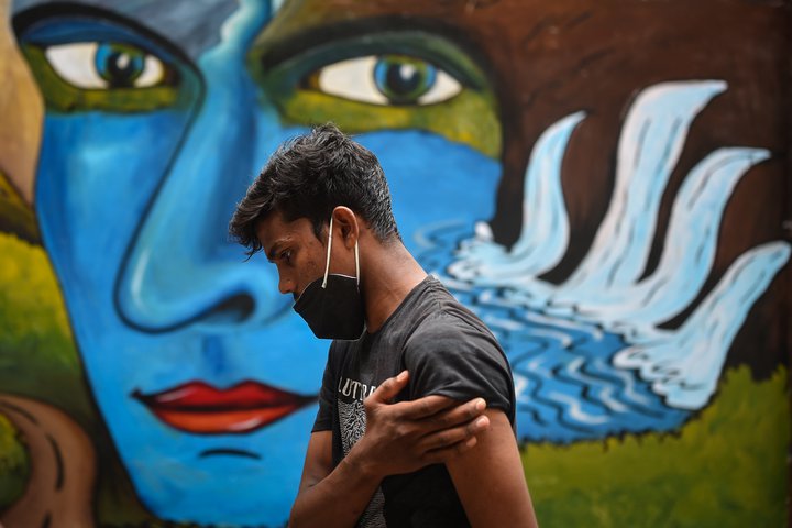 Karlmaður heldur um upphandlegginn eftir að hafa fengið bólusetningu á Indlandi. Þar varð delta-afbrigðið til í óbólusettu samfélagi með þekktum og skelfilegum afleiðingum.