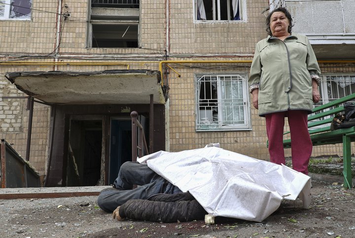 Kona stendur við lík manns eftir árás Rússa í borginni Kharkiv.