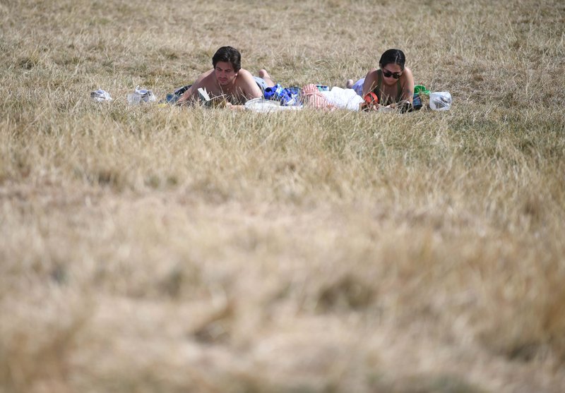Legið í sólbaði á skrælnuðu grasi á Suður-Englandi. Mynd: EPA