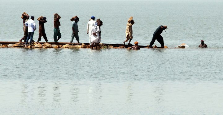 Gengið eftir járnbrautarteinum í flóðvatni í Sindh-héraði.